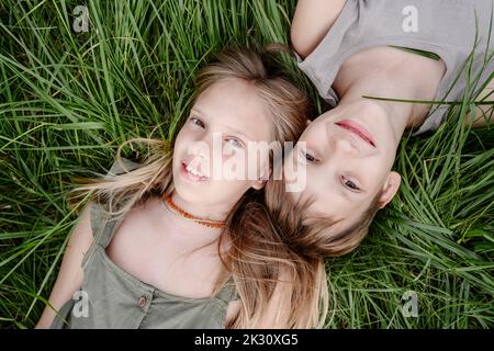 Brother and sister lying down on grass Stock Photo