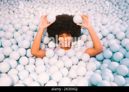 Happy young woman playing amidst ball pool Stock Photo