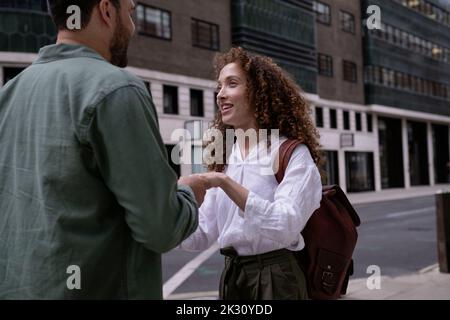 Smiling young woman holding hand with man at footpath Stock Photo