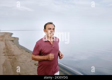 Senior man running at beach Stock Photo