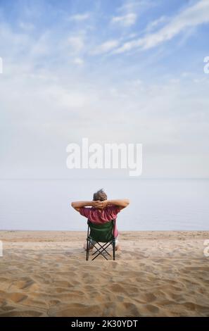 Man relaxing sitting on folding chair at beach Stock Photo