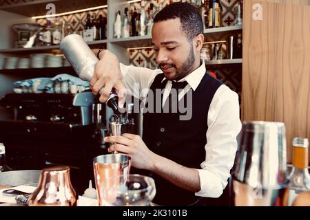 Bartender pouring syrup from bottle into jigger at bar Stock Photo
