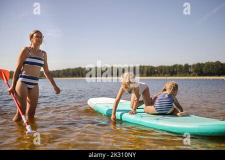 Mother with daughter having fun on paddle board Stock Photo