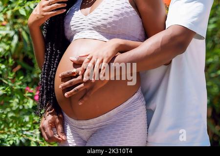 Man embracing pregnant woman stomach on sunny day Stock Photo