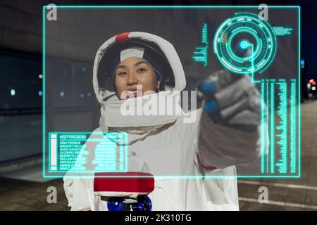 Young woman wearing astronaut costume touching device screen Stock Photo