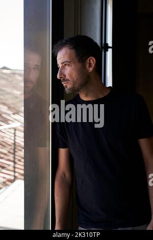 Sad man looking through window Stock Photo