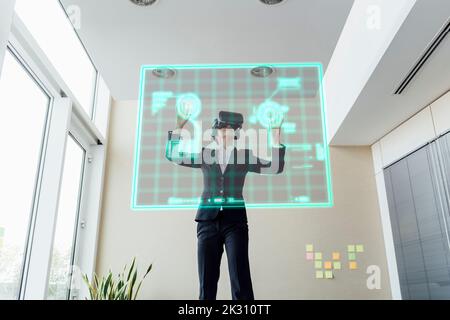 Businesswoman working on transparent screen in office Stock Photo