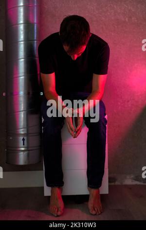 Depressed man sitting on stool at home Stock Photo