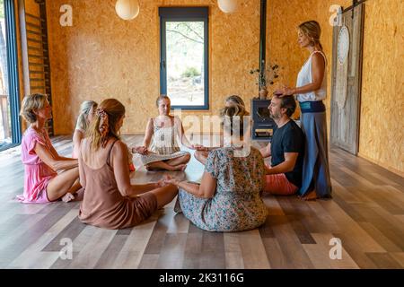 Group of friends practicing meditation together in yoga class Stock Photo