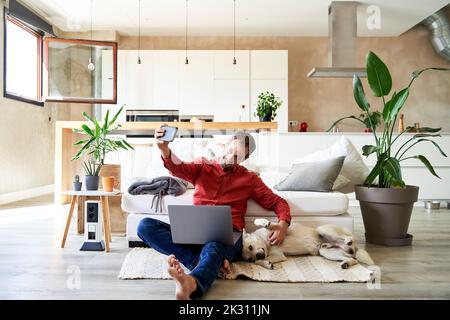 Businessman taking selfie with dog through mobile phone Stock Photo