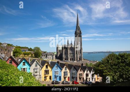 Ireland, County Cork, Cobh, Colorful row houses standing along steep street with Saint Colmans Cathedral in background Stock Photo