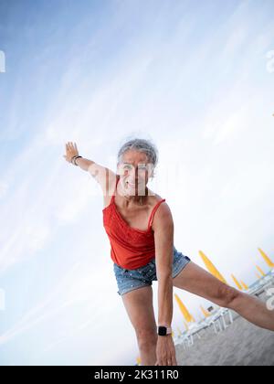 Happy senior woman doing exercise at beach Stock Photo