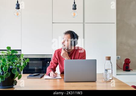 Thoughtful freelancer sitting with laptop at home Stock Photo
