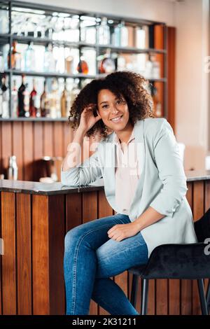 Smiling woman sitting on chair in bar Stock Photo