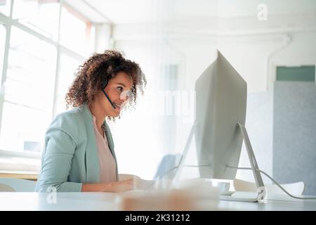 Smiling businesswoman working on computer in office Stock Photo