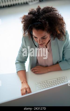 Customer service representative working on computer at desk in office Stock Photo