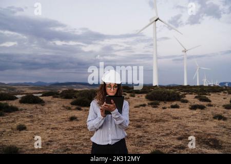 Engineer working on tablet PC at wind farm Stock Photo