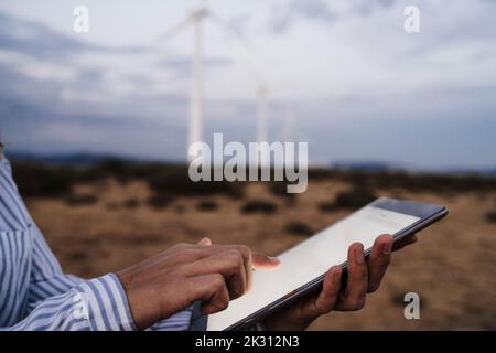 Hand of engineer touching screen of tablet PC at wind farm Stock Photo