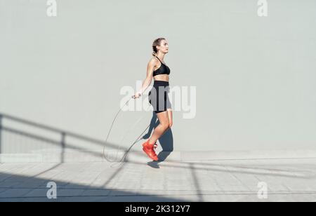 Young athlete skipping rope on sunny day Stock Photo