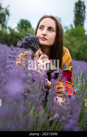 Thoughtful woman with bouquet of fresh lavender flowers at field Stock Photo