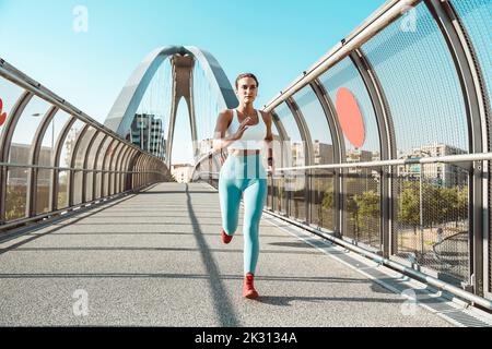 Young woman running on footbridge Stock Photo