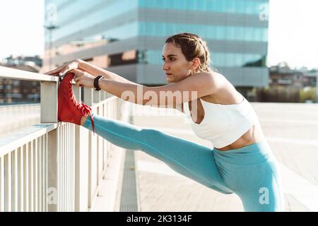 Young woman stretching leg on railing Stock Photo