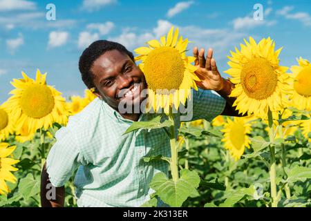 Happy young man posing with sunflower in field Stock Photo