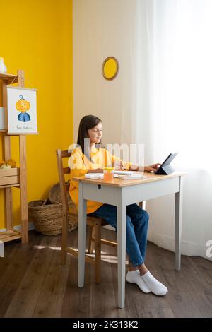 Girl using digital tablet PC sitting at table Stock Photo