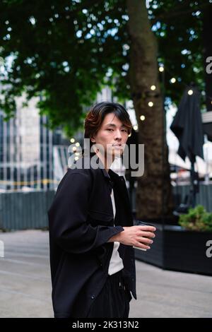 Young man with coffee cup standing on footpath Stock Photo