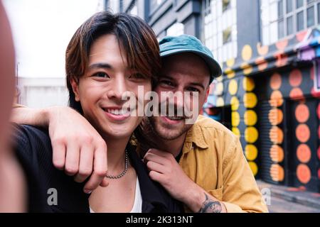 Smiling gay couple taking selfie in city Stock Photo