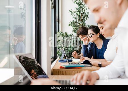 Business people working together sitting by window at workplace Stock Photo