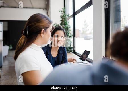 Businesswoman sharing ideas with colleagues in office Stock Photo
