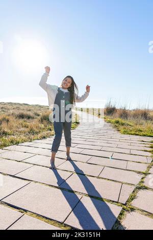 Happy girl having fun dancing on footpath Stock Photo