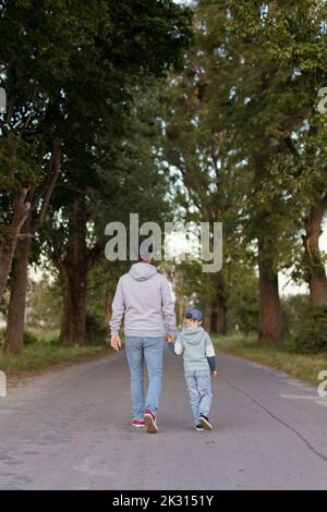 Man holding son's hand walking on footpath Stock Photo