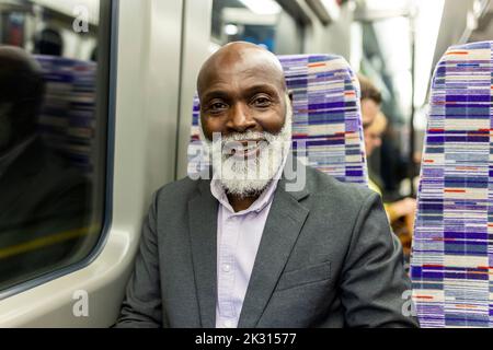 Smiling commuter with beard traveling in train Stock Photo
