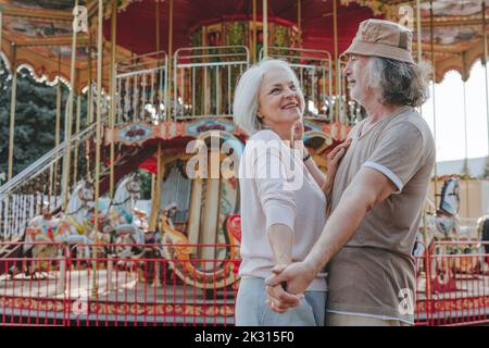 Happy couple holding hands dancing together in amusement park Stock Photo