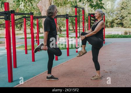 Active couple stretching legs in park Stock Photo
