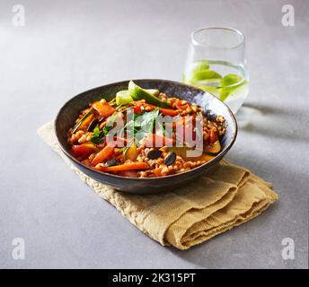 Ready-to-eat bowl of cooked grains with vegetables, pumpkin seeds, parsley and lime Stock Photo
