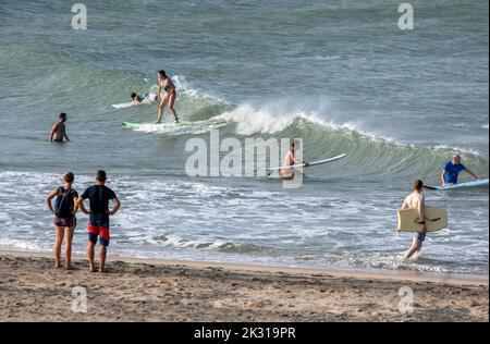 Foreign surfers ride the shore break waves off Elephant Rock near Arugam Bay on the east coast of Sri Lanka. Stock Photo