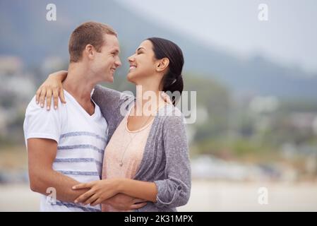 Sharing a loving gaze. a young couple kissing at the beach. Stock Photo