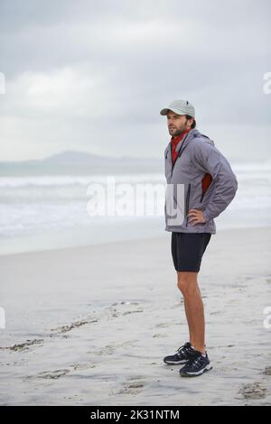 Taking a morning run on the beach. Full length shot of a handsome young man standing on a beach. Stock Photo