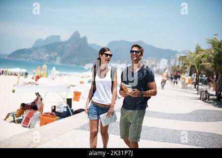 Strolling along through paradise. a young couple walking beside the beach. Stock Photo