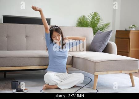 Work from home concept, Business women sit on floor and stretching to relax after working at home. Stock Photo