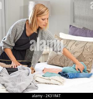 Where are my other jeans. a young woman packing her suitcase. Stock Photo