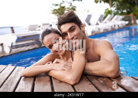 Theyre enjoying their holiday together. Portrait of an attractive young couple relaxing in a pool. Stock Photo
