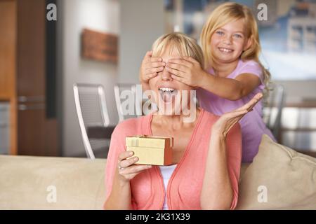 Open your hands and close your eyes for a big surprise. a young girl surprising her mother with a gift. Stock Photo