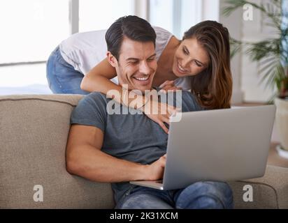 You make me feel so happy. An affectionate young couple using a laptop in their home. Stock Photo