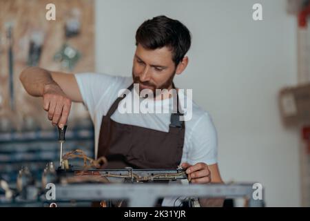 Smiling young worker repairing coffee machine in a workshop Stock Photo