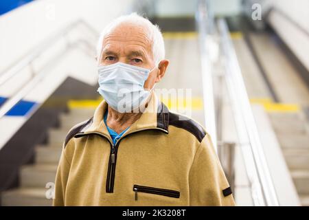 Portrait of old man in mask going to metro station Stock Photo