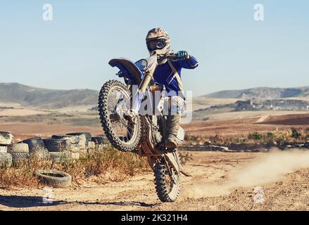 Hes got total control over the horsepower he wields. a motocross driver performing a wheelie during a race. Stock Photo